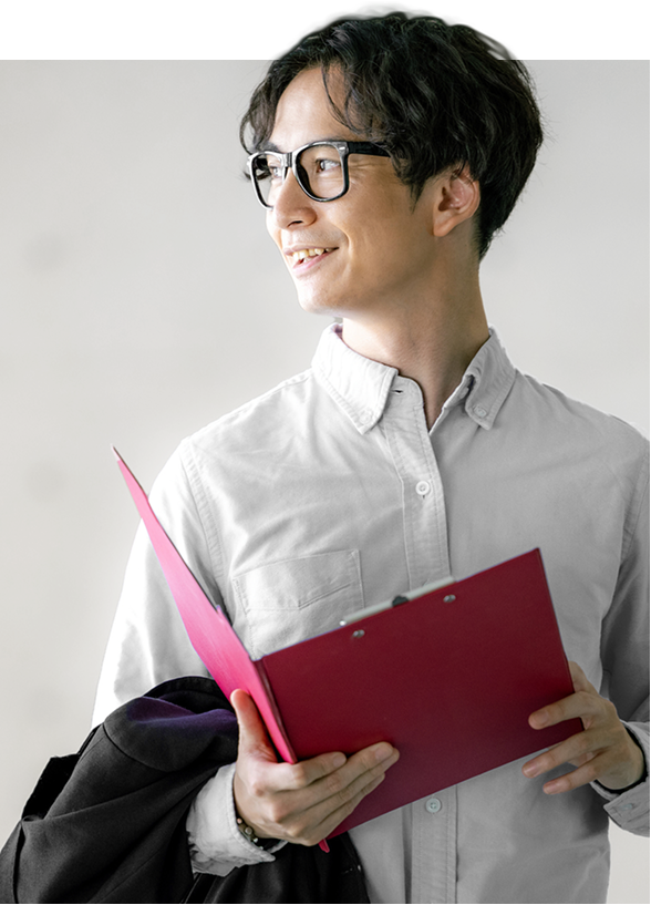 笑顔でオフィスのデスクに座る女性 赤いファイルを手に持ち、横を向いて微笑む男性